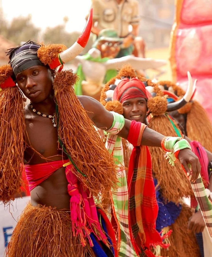 Dançarinos em traje de festa, saias de ráfia e toucados com cornos, numa festa tradicional na Guiné-Bissau